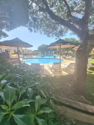 a swimming pool with chairs and umbrellas at Apart T2 praia dos bicos in Albufeira