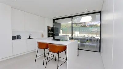 a kitchen with a white counter and orange chairs at OneSixOne-Cleverdetails, Luxury villa, Sleeps 8 adults 2 children, Private pool and Jacuzzi in Vilamoura