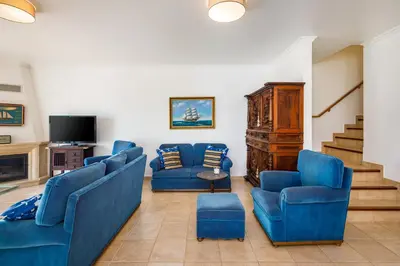 a living room with blue couches and a tv at Falésia Ocean Villa by The Portuguese Butler in Albufeira