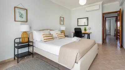 a bedroom with a white bed and a desk at Albufeira 3BR with Pool and AC by the beach by LovelyStay in Albufeira