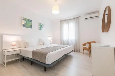 a white bedroom with a large bed and a table at Apartamentos Baltum in Albufeira