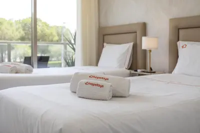 two beds in a hotel room with towels on them at Hopstays - Vila das Lagoas - Salgados in Albufeira