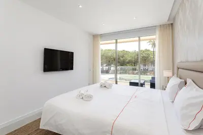 a bedroom with a large white bed with a tv at Hopstays - Vila das Lagoas - Salgados in Albufeira