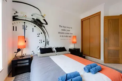 a bedroom with a large clock on the wall at ROJA PÉ - Elegante apartamento T2 com AC perto do Pine Cliffs in Albufeira