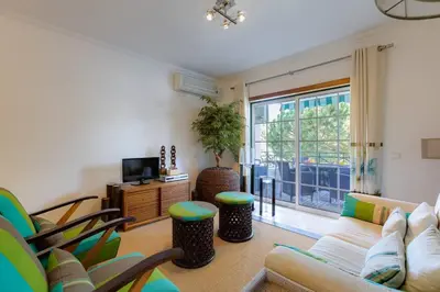 a living room with a couch and chairs and a tv at ROJA PÉ - Elegante apartamento T2 com AC perto do Pine Cliffs in Albufeira