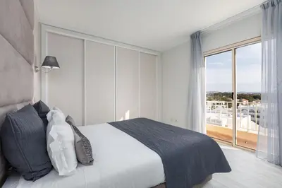 a bedroom with a bed and a large window at D_Loft in Albufeira