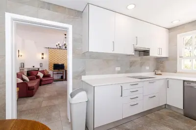 a kitchen with white cabinets and a living room at Villa Fineli in Vilamoura