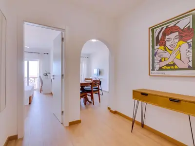 a living room with a table and a painting on the wall at AL - Apartamento Girassol Beach Front Quarteira in Quarteira