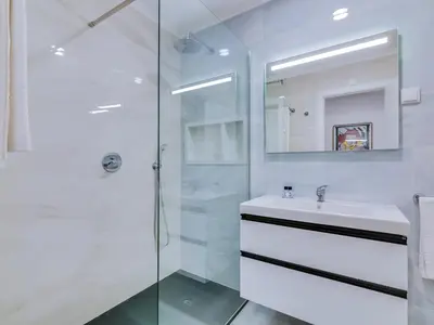 a white bathroom with a sink and a shower at AL - Apartamento Girassol Beach Front Quarteira in Quarteira