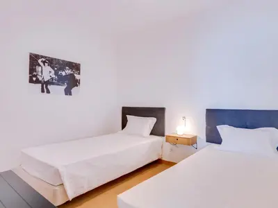 two beds in a room with white walls at AL - Apartamento Girassol Beach Front Quarteira in Quarteira