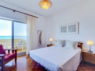a bedroom with a bed and a balcony with the ocean at AL - Apartamento Maré Alta in Quarteira