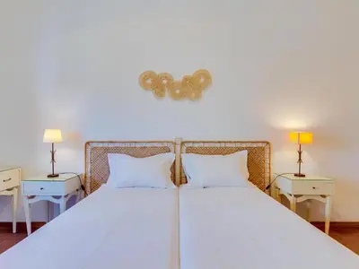 a white bed with two pillows and two tables at AL - Apartamento Maré Alta in Quarteira