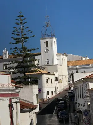 a white building with a clock tower on a street at Apartamento Flor de Amendoeira in Albufeira