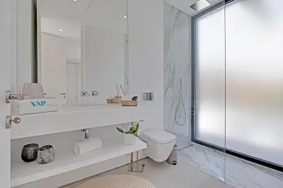 a bathroom with a toilet and a glass shower at One Six Villa in Vilamoura