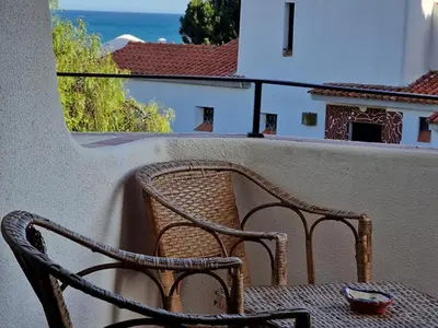 a wicker chair sitting on a balcony looking out at the ocean at Akisol Albufeira Euphoria in Albufeira