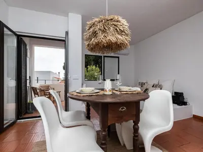 a dining room with a table and white chairs at Akisol Albufeira Euphoria in Albufeira