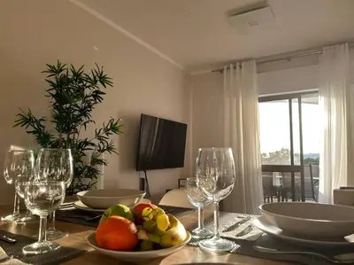 a dining room table with a bowl of fruit and wine glasses at Falésia Beach Apartment in Albufeira