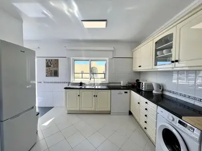 a white kitchen with a sink and a dishwasher at Faro Rising by Homing in Faro