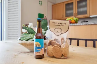 a bottle of beer sitting on a table with a bag of bread at Bicos Beach Apartments By Albufeira Rental in Albufeira