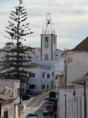 a tall white building with a clock tower on a street at The Best Downtown Albufeira in Albufeira