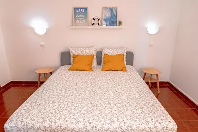 a bedroom with a large bed with two orange pillows at Cozy Albufeira Charm in Albufeira