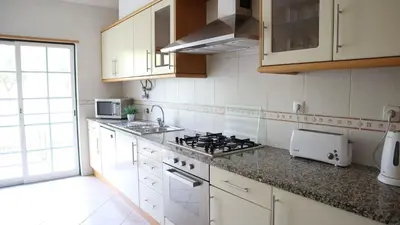 a kitchen with white cabinets and a stove top oven at São Vicente By Albufeira Rental in Albufeira