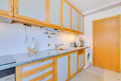 a kitchen with wooden cabinets and a sink at AL - Apartamento Falésia Flat in Vilamoura