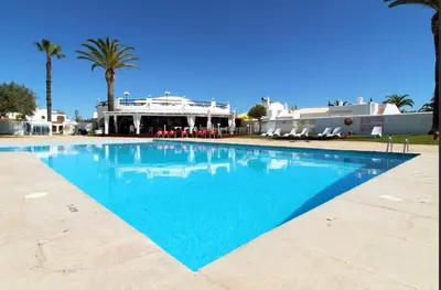 a large swimming pool with palm trees and a building at Villa Bougainvilla - Vilamoura - Pool - Free wifi - Air con in Quarteira