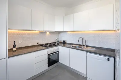 a white kitchen with white cabinets and a sink at Casa Relax à Olhos Albufeira in Albufeira