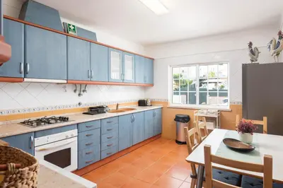 a kitchen with blue cabinets and a table and a dining room at JUDY - Albufeira in Albufeira