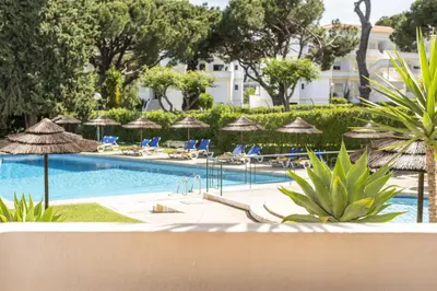 a swimming pool with chairs and umbrellas at a resort at Alvaflor 102 - Vilamoura by HD Properties in Vilamoura