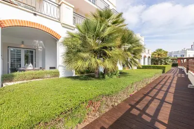 a palm tree next to a building with a sidewalk at Vilamoura Marina Lake in Vilamoura