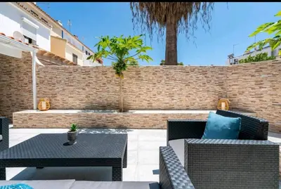 a patio with chairs and tables and a brick wall at Marina Holiday House in Quarteira