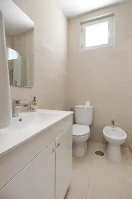 a white bathroom with a toilet and a sink at Pool side Villa Zara in Albufeira