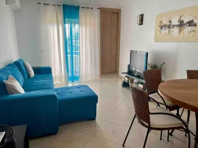 a living room with a blue couch and a table at Vilamoura-Praia da Falésia T2 in Quarteira