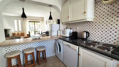a kitchen with white cabinets and a counter with stools at Sao Rafael T2 Duplex, Albufeira in Albufeira