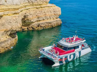 a boat in the water next to a cliff at Luxury Apart wStunning Sea Views, Walk Beach in Albufeira