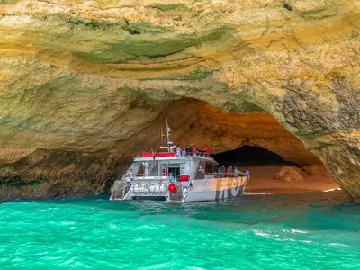a boat in the water in front of a cave at Luxury Apart wStunning Sea Views, Walk Beach in Albufeira