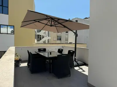a table with chairs and an umbrella on a balcony at A Casa da Elsa in Faro
