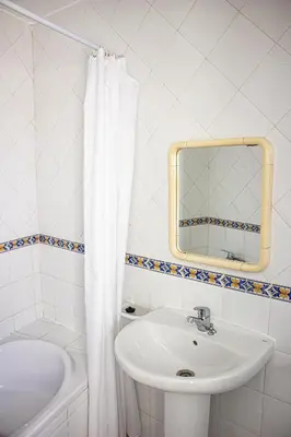 a white bathroom with a sink and a mirror at Casa Clementina in Albufeira