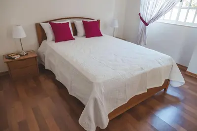 a bedroom with a large white bed with pink pillows at Casa das Palmeiras - Villa com piscina, BBQ e ar condicionado in Albufeira