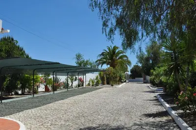a walkway with a canopy and palm trees in a park at Casa Areias Boutique Apartments in Albufeira