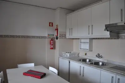 a kitchen with white cabinets and a table and a sink at Casa Areias Boutique Apartments in Albufeira
