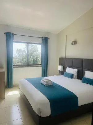 a bedroom with a large bed with blue curtains and a window at Casa Areias Boutique Apartments in Albufeira