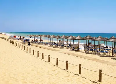 a row of umbrellas and chairs on a beach at Herdade dos Salgados - 2 Bedroom in Guia