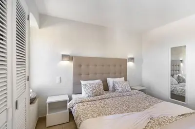 a white bedroom with a bed and a mirror at Garden Paradise, Old Town & Beach in Albufeira