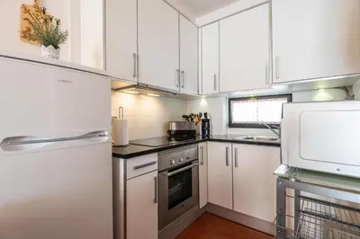 a kitchen with a table and a white refrigerator at Albufeira Jardim Sun Deck Studio in Albufeira