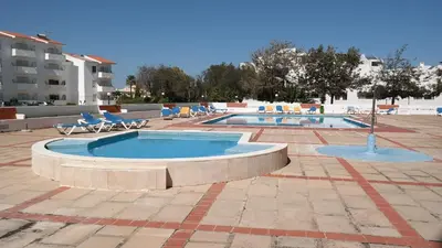 a swimming pool with lounge chairs in a resort at Coral By Albufeira Rental in Albufeira