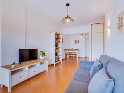 a living room with a blue couch and a tv at AL - Apartamento Village Atlântico in Vilamoura