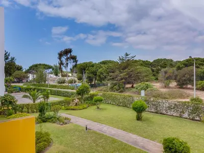 a garden with a stone wall and grass and trees at AL - Apartamento Village Atlântico in Vilamoura